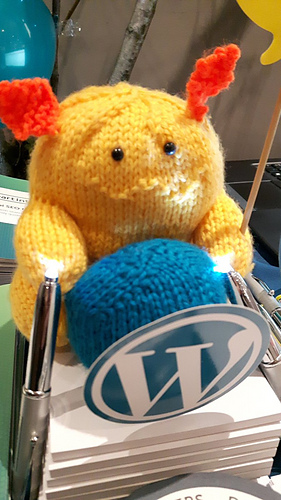 Wapuu sitting with his WordPress ball with lights pointing at him