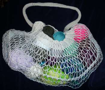 A version of the Yarn Stash bag in white cotton, filled with balls of yarn
